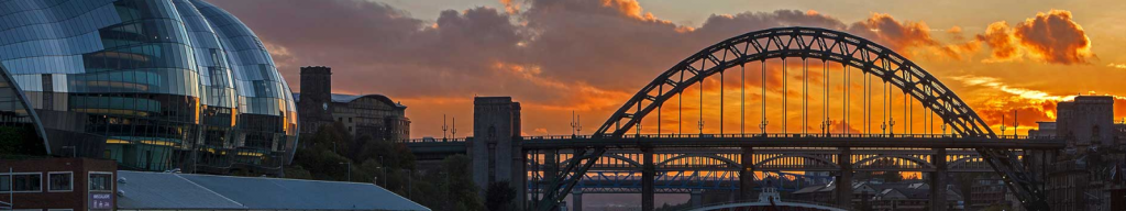 The image features a bridge silhouetted against a striking sunset.
