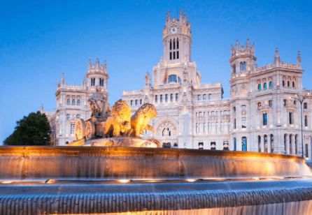 a large white building, possibly a palace or landmark, situated in front of a fountain.